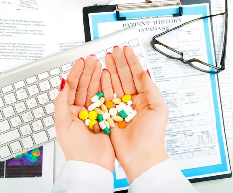 a closeup of hands holding a lot of pills above a workdesk