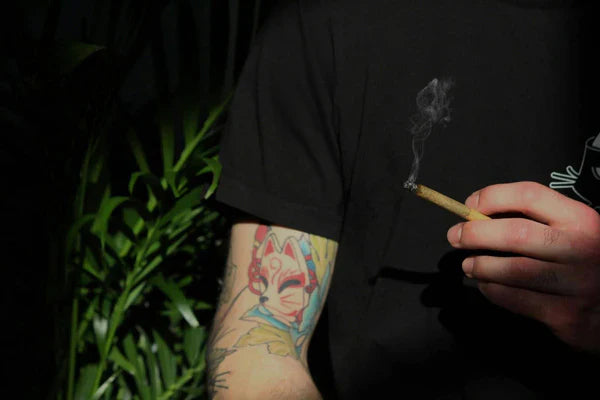 A man holding a lit cannabis joint