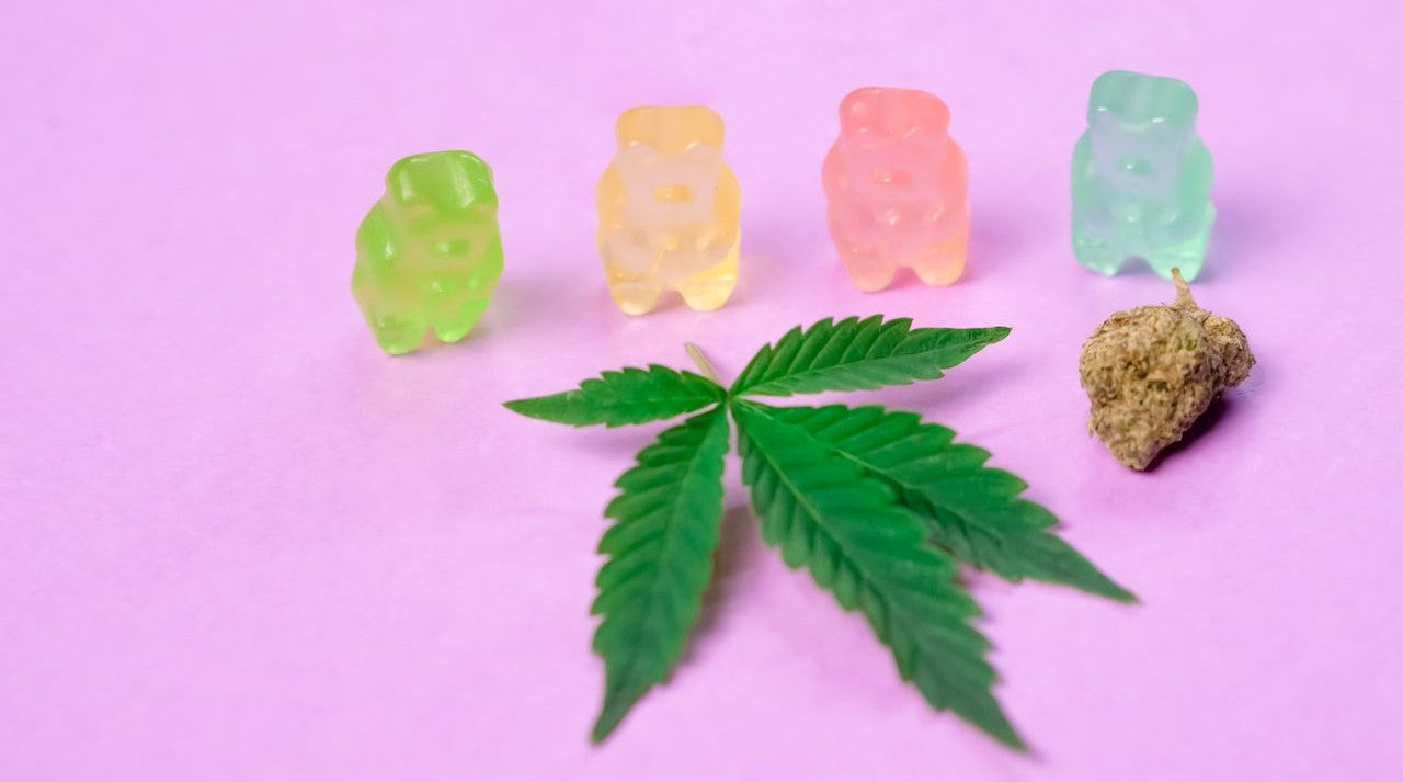 Edible THC gummies next to a cannabis leaf and flower