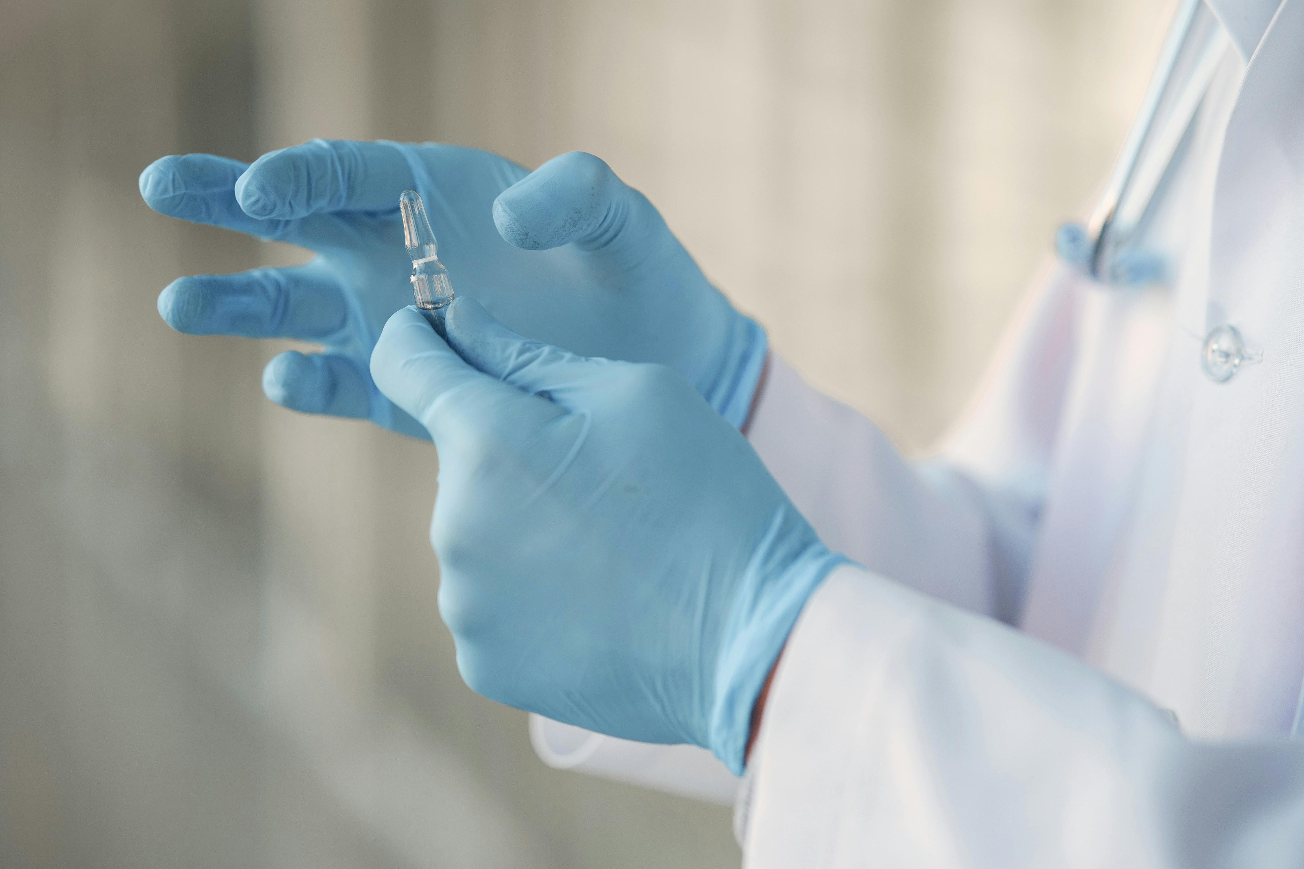 Closeup of medical worker's hands in gloves, holding an ampule of naloxone