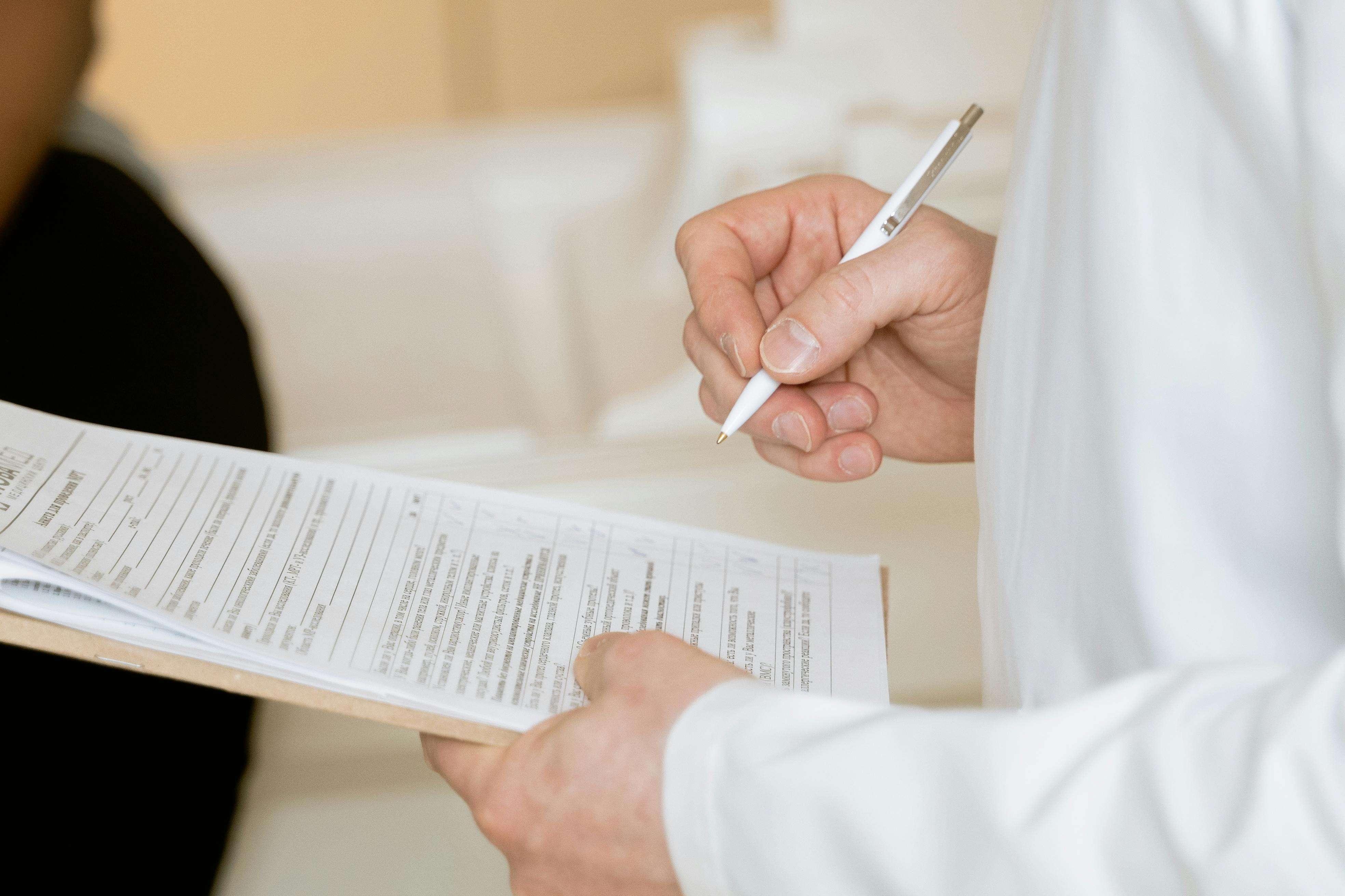 Doctor or lab technician filling out a diagnostic form or patient drug screening record on a clipboard