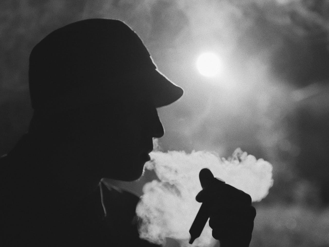 A an obscured man smoking from a small pipe, surrounded by white smoke